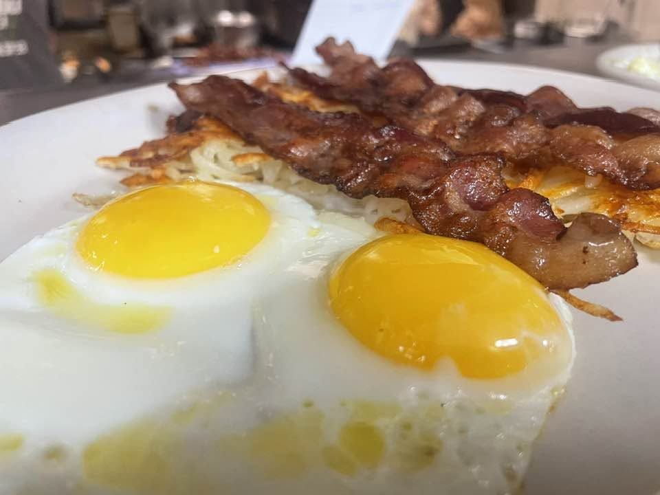 Two sunny-side-up eggs with crisp bacon and hash browns