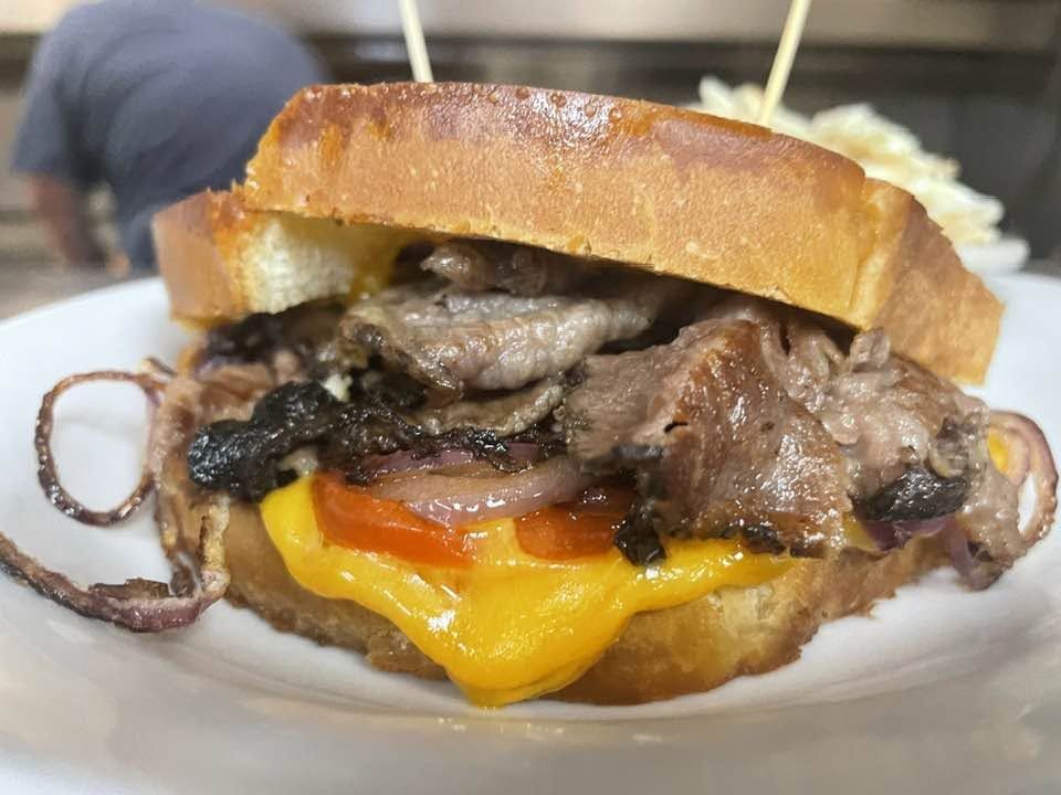 Beef melt with grilled onions, tomato and melted cheddar on toasted bread