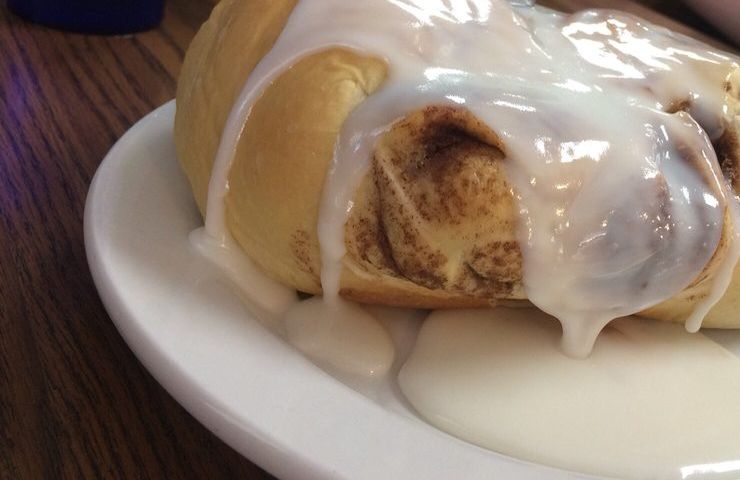 An oversized cinnamon roll dripping with white icing